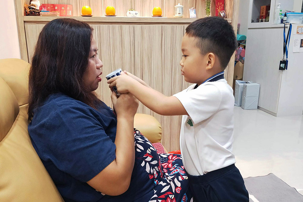 Due to Singapore’s COVID situation, the venue for the Parents Appreciation Day had to be switched to each student’s home in 2021. Lee Junyi is seen serving tea to his then-pregnant mother, Jeslyn Woon. (Photo provided by Jeslyn Woon)