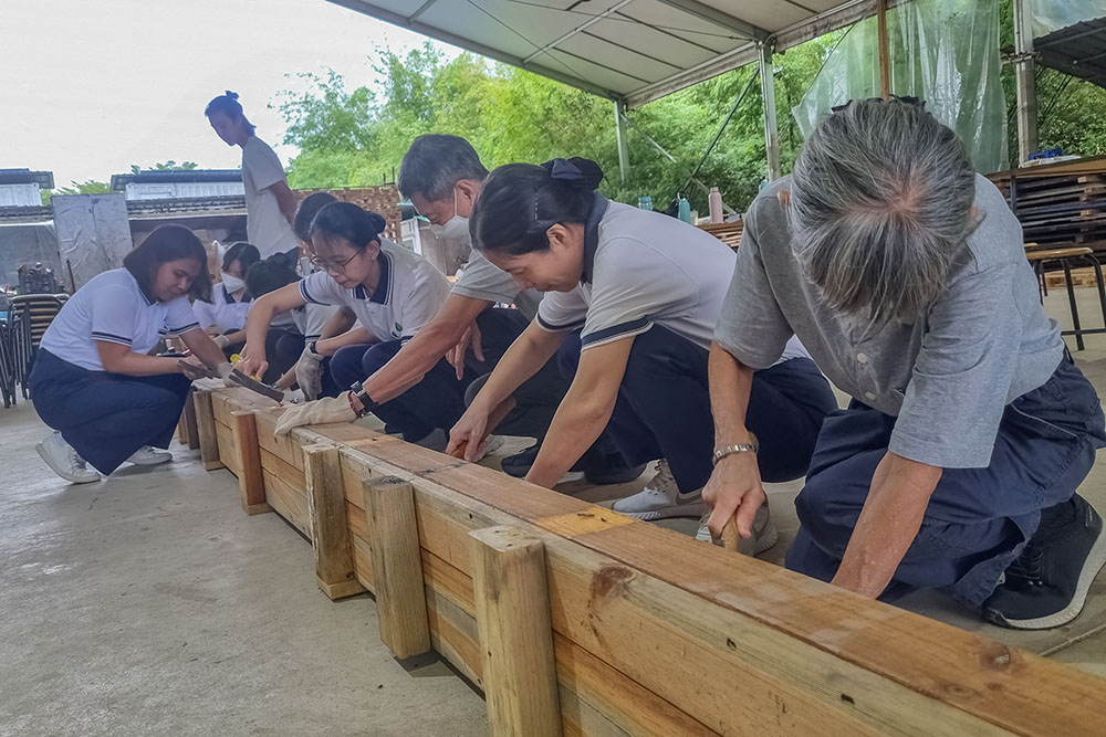 The teachers focus on removing the nails from recycled wood one by one so that the wood can be reused. (Photo by Audrey Koh)